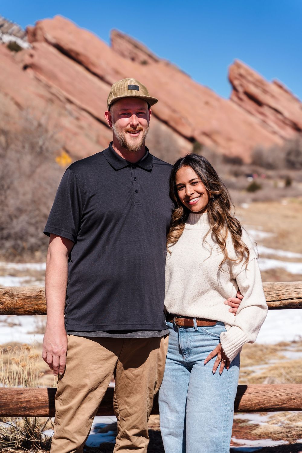 Couple smiling together at Red Rocks Park, Colorado, with iconic red sandstone formations in the background.