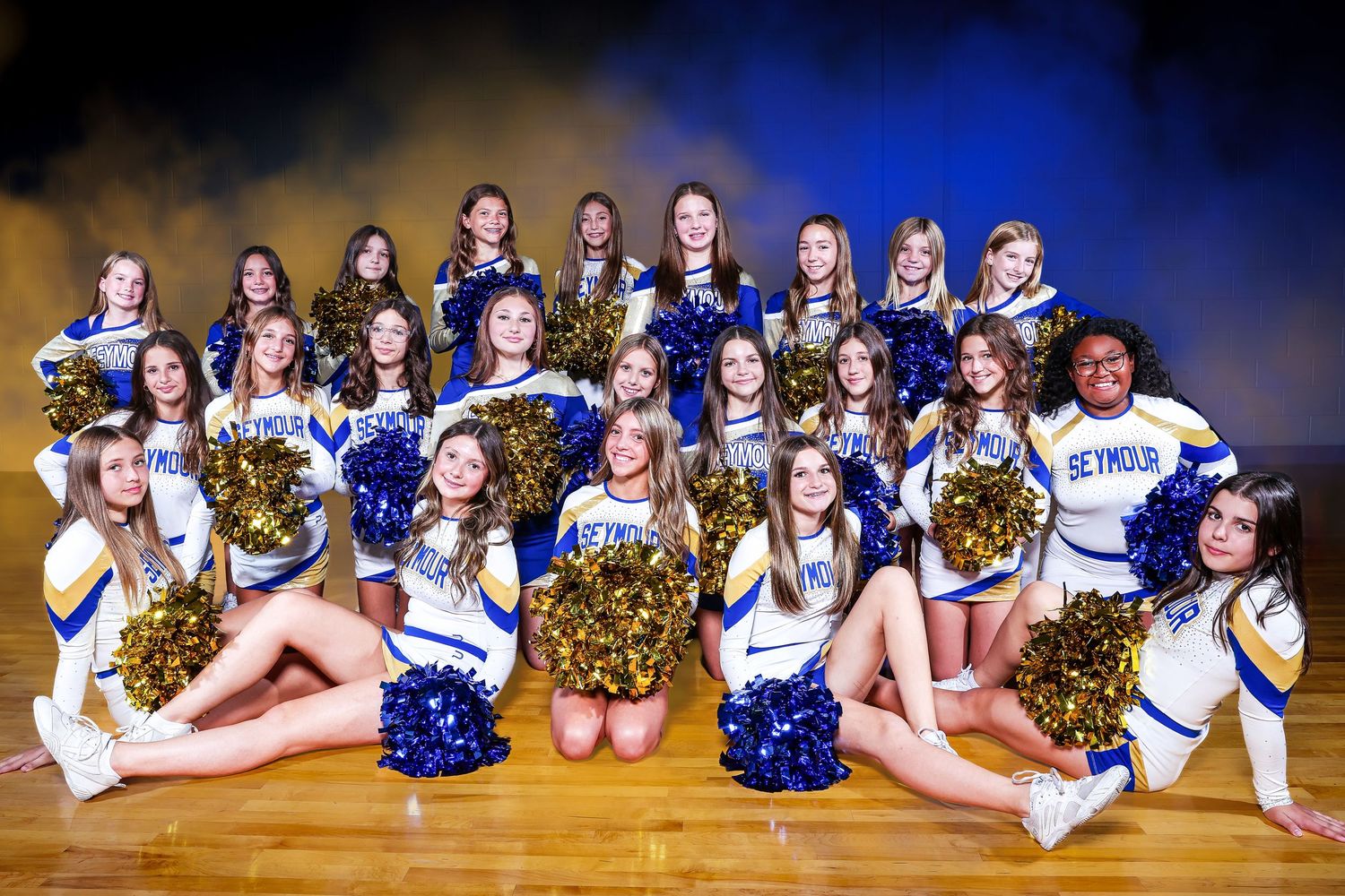 Seymour high school cheerleading squad posing in blue and gold uniforms with pom-poms on a gymnasium floor.