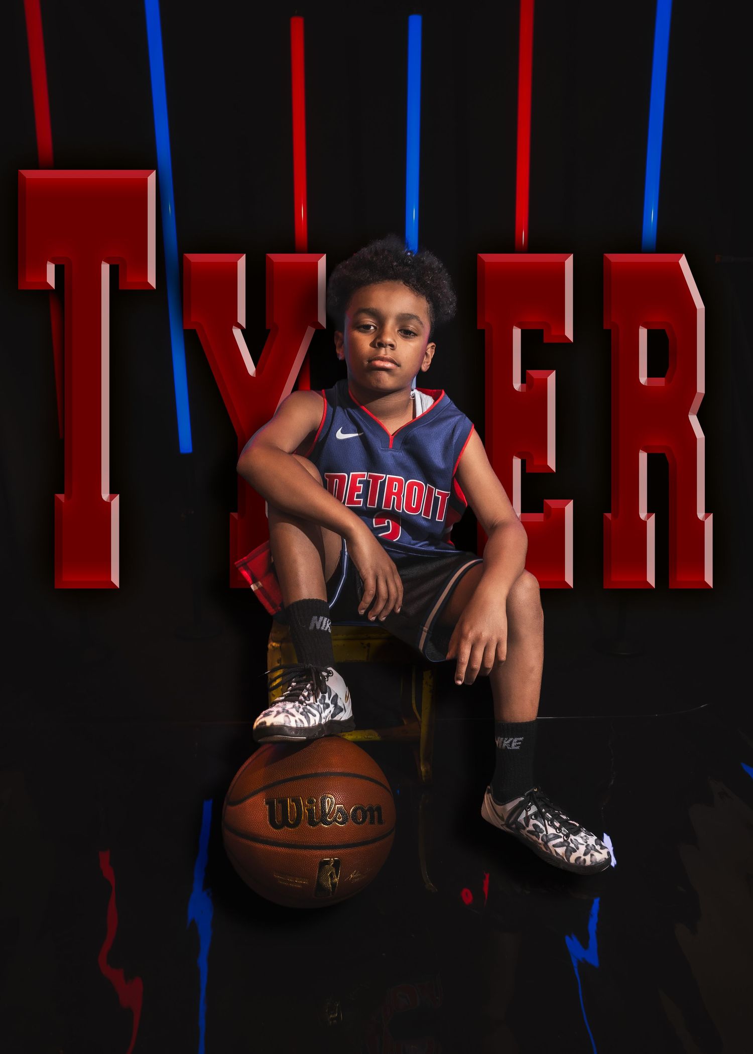 A young boy named Tyler sits on a basketball in a Detroit jersey against a bold red and black graphic backdrop.