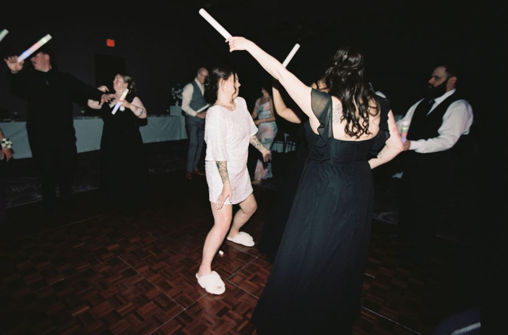 Guests dancing and celebrating with light sticks on the dance floor at a wedding reception.