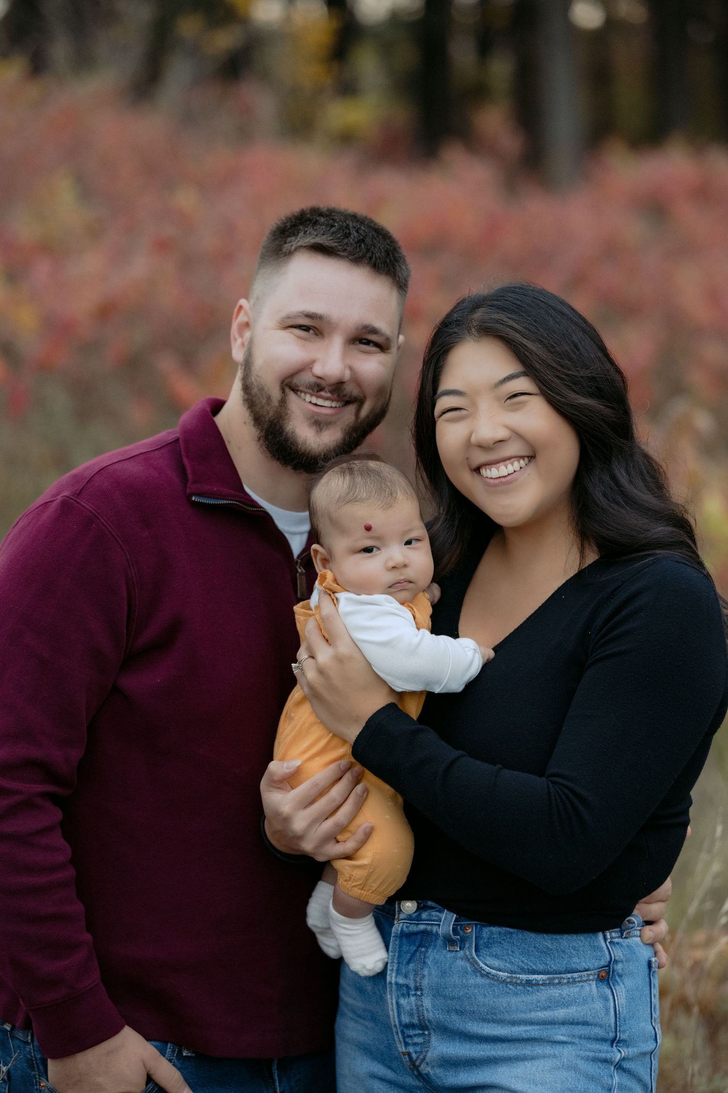 a beautiful family portrait of young parents with their first baby during fall mini session in hudson wisconsin