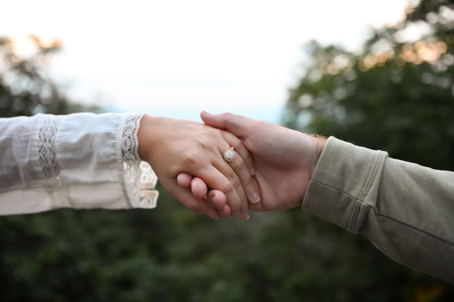 Couple embracing while overlooking stunning Blue Ridge Mountain landscape from scenic overlook at sunset.