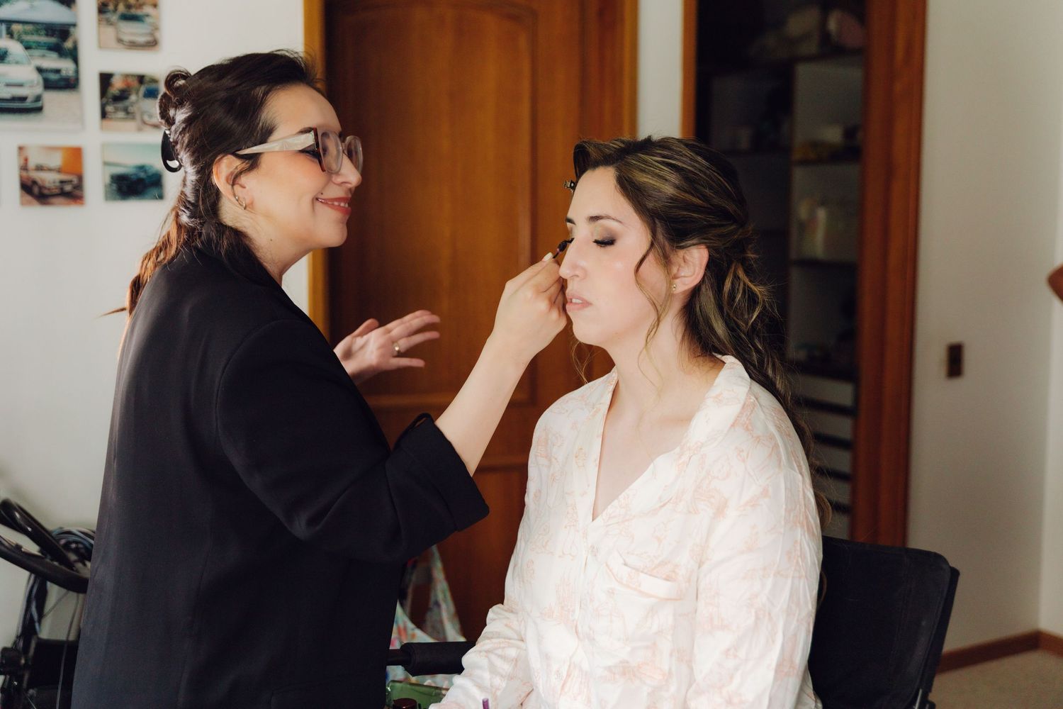 Professional makeup artist carefully applying finishing touches to brides face during bridal preparation.