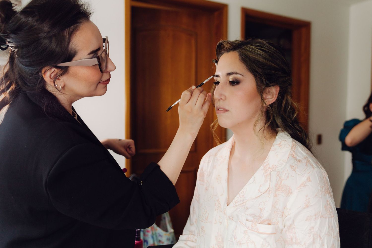 Makeup artist applying eyeshadow to a bride during wedding preparations.