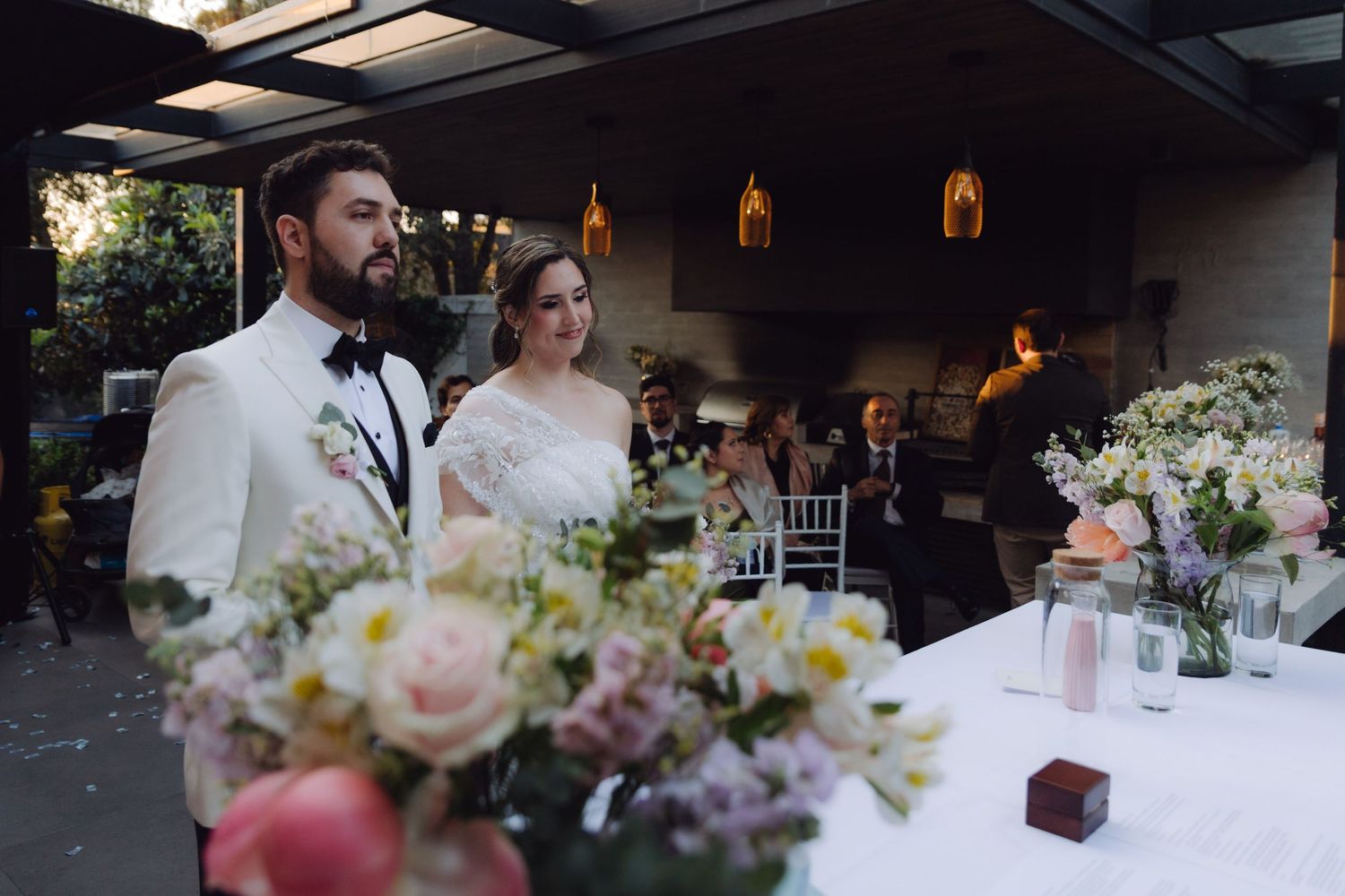 Bride and groom stand together at the altar during their outdoor wedding ceremony with floral arrangements.