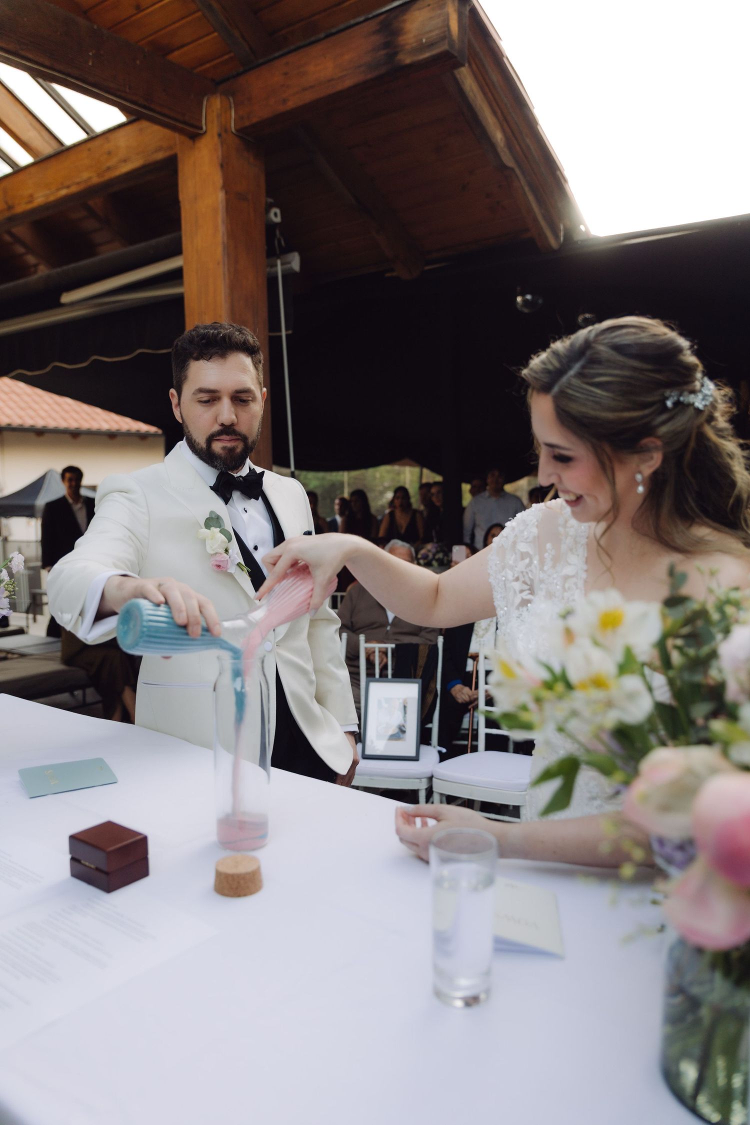 Bride and groom perform a sand unity ceremony, pouring colorful sand into a vase at their wedding reception.