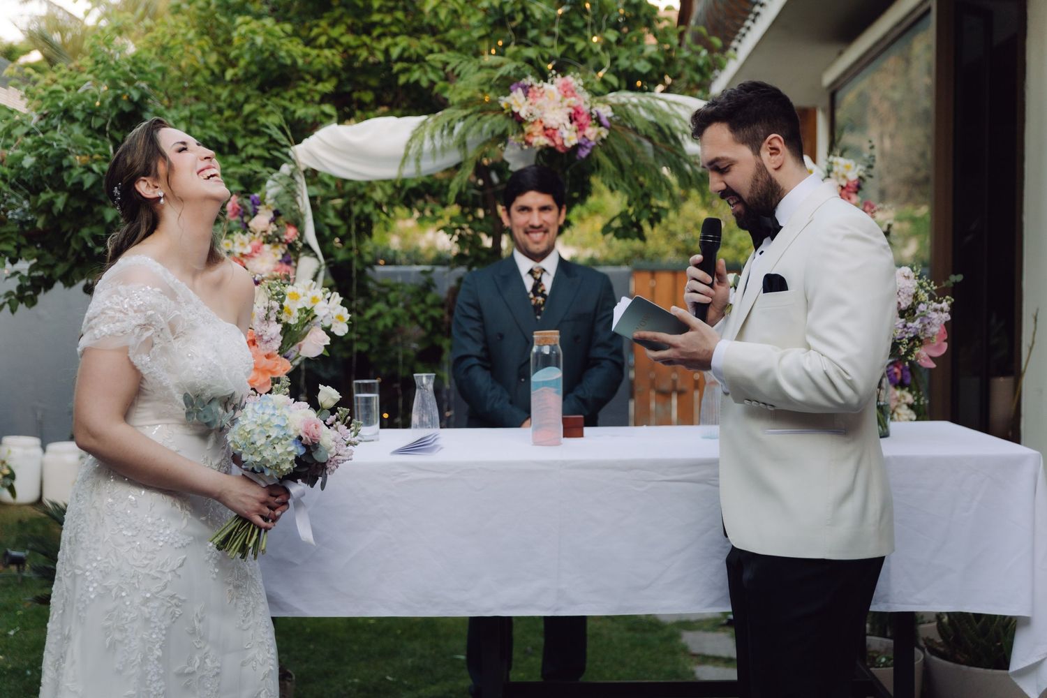Groom reads his vows as the bride laughs joyfully during a romantic outdoor wedding ceremony.