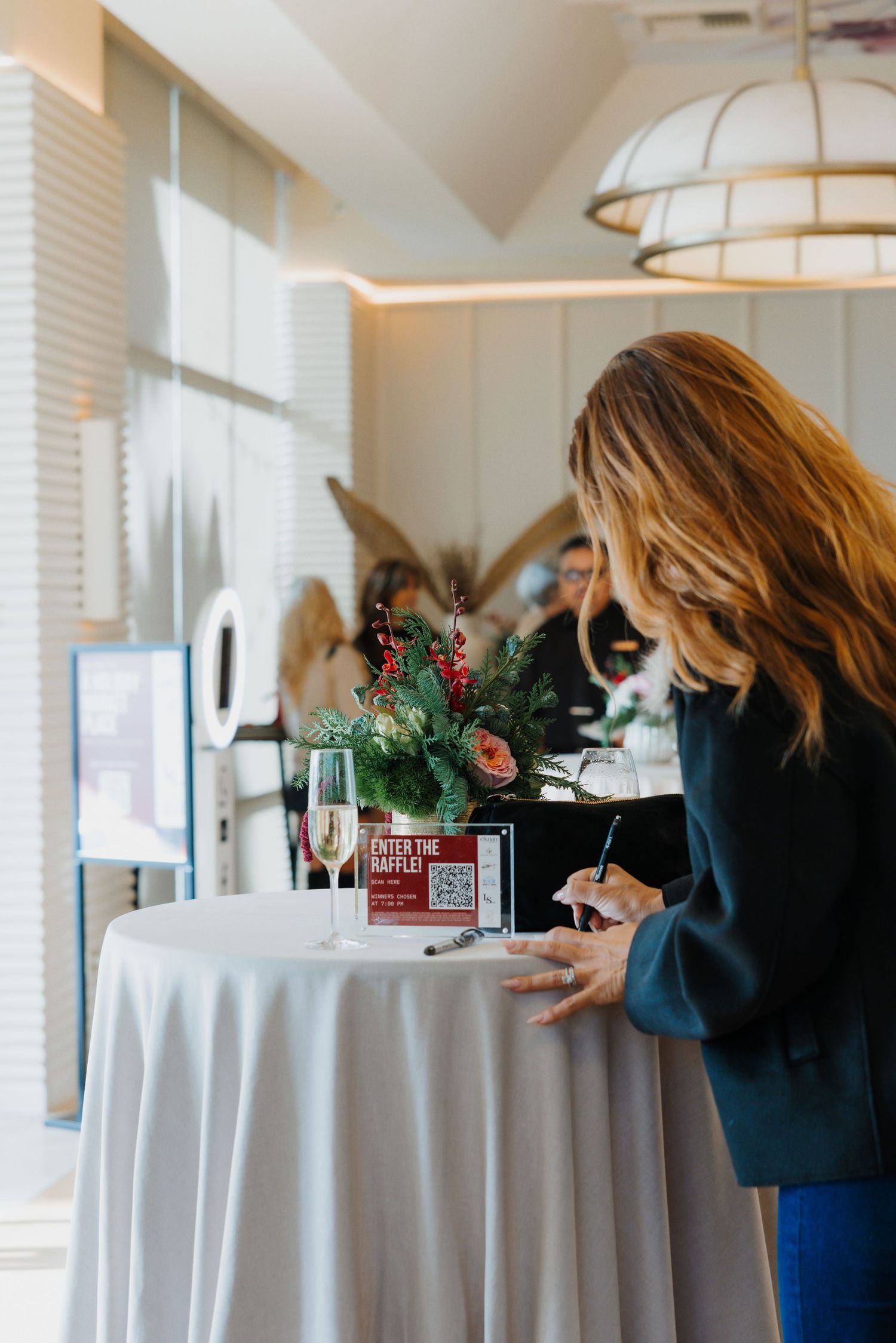 Professionals networking at a corporate cocktail event with wine bottles and drinks on a bar counter.