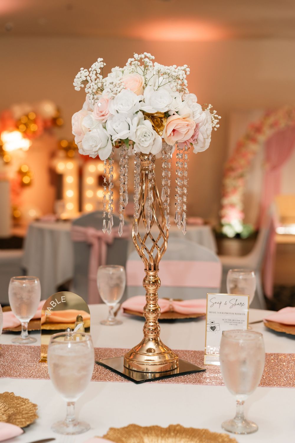 Elegant gold candelabra centerpiece with pink and white roses and crystal accents on a rose gold sequin tablecloth.
