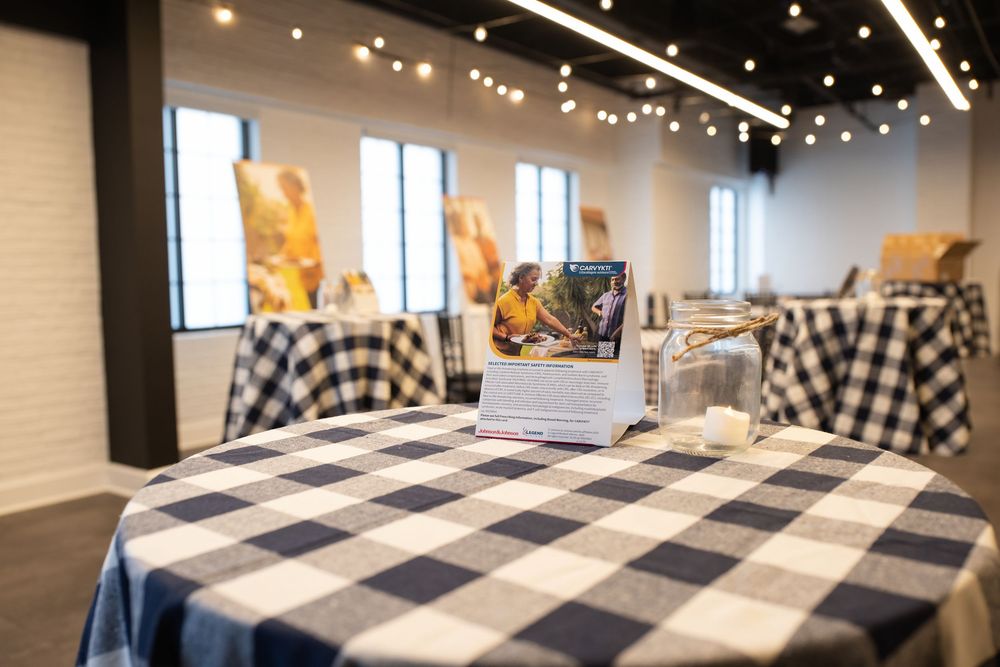 Elegant event space with black and white checkered tablecloths, string lights, and decorative centerpieces.