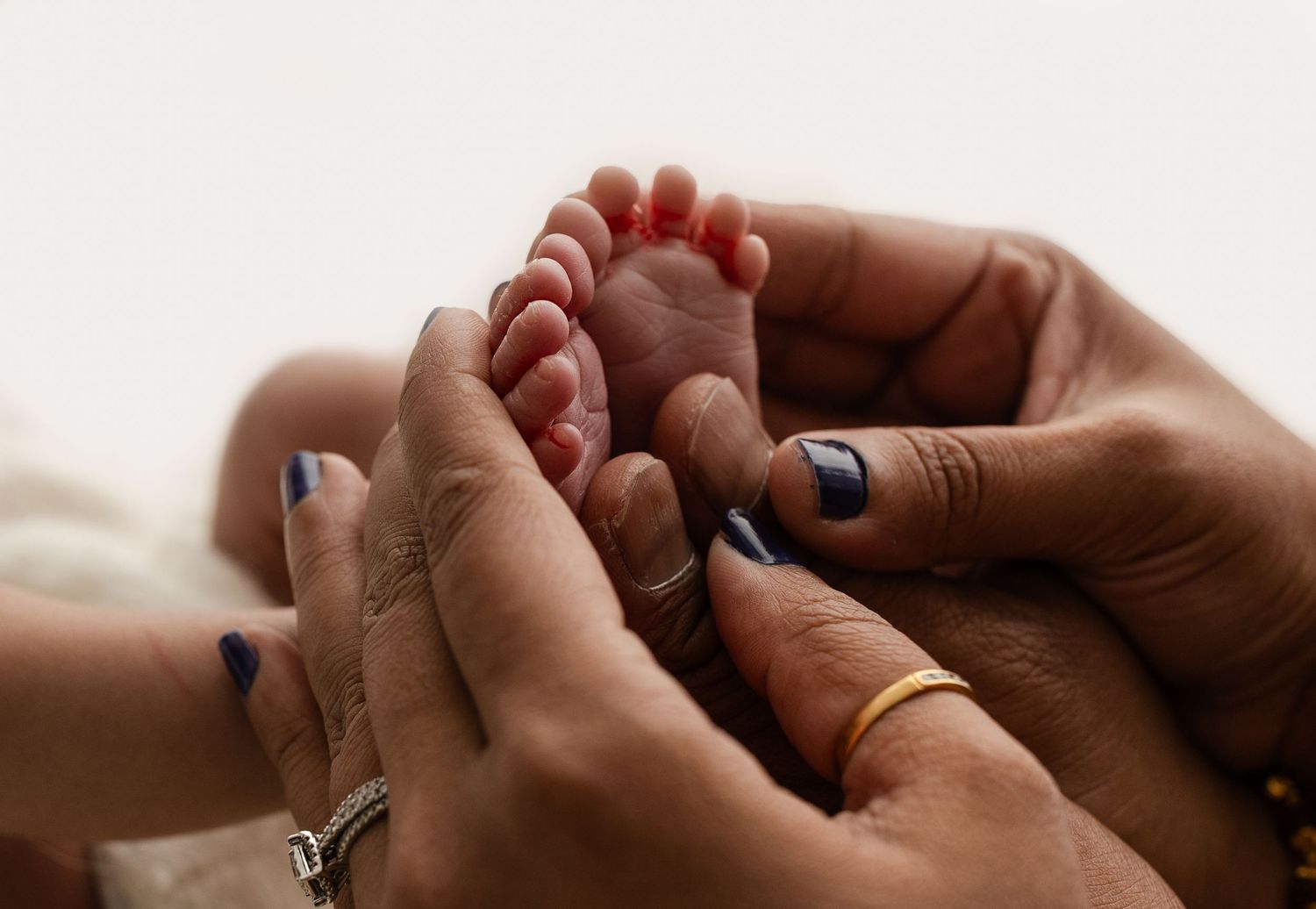 New parents lovingly hold their baby's tiny feet for a backlit detail shot, captured by Charlottesville newborn photographer.