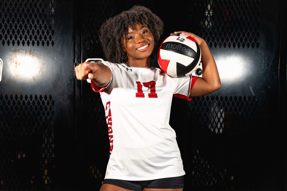 Female volleyball player in number 17 jersey holds ball and points.