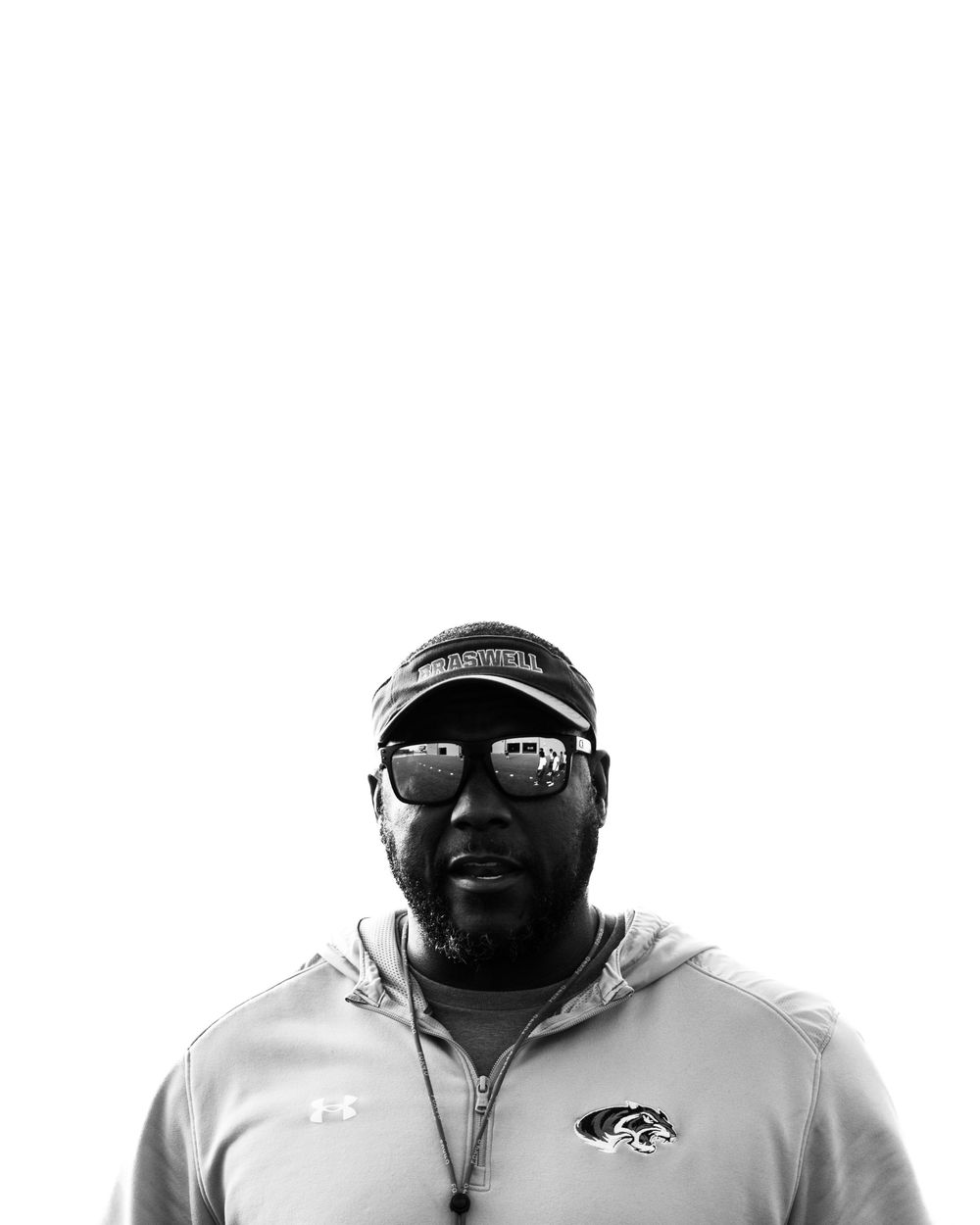 Black and white portrait of male coach in cap and sunglasses.