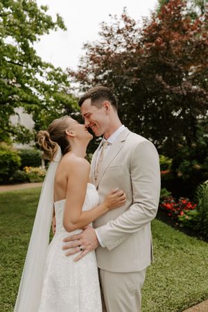 Bride and groom sharing romantic moment about to kiss in lush garden setting.
