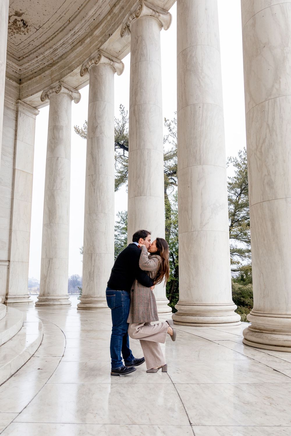 Couple sharing a romantic kiss among white marble columns at the Jefferson Memorial in Washington DC.