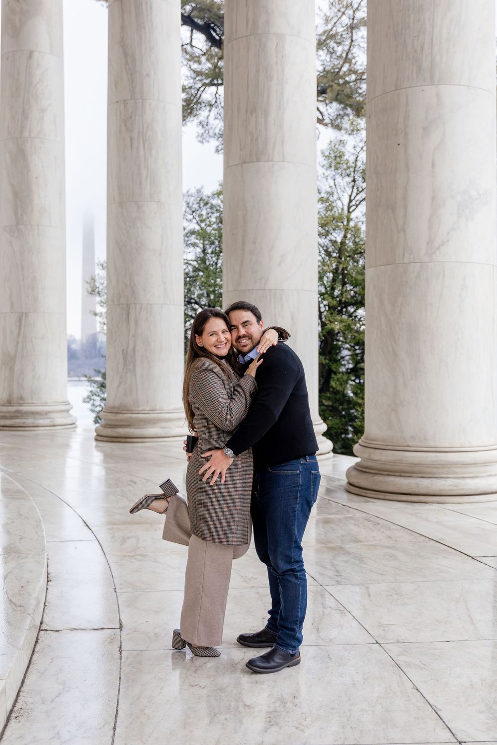Happy engaged couple embracing and smiling among the grand marble columns of the Jefferson Memorial.
