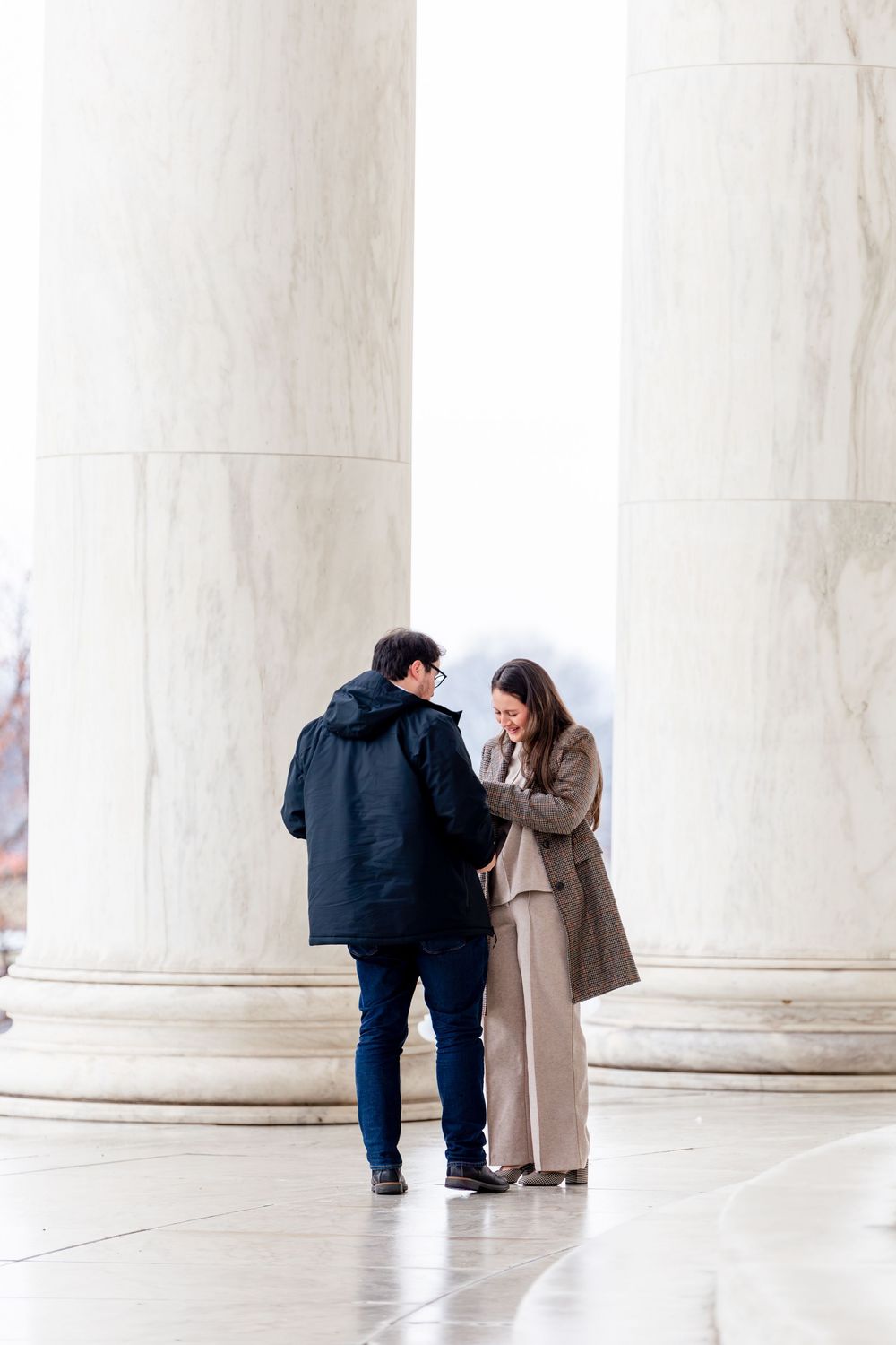 Couple sharing a tender moment between marble columns at the Jefferson Memorial in Washington, D.C.