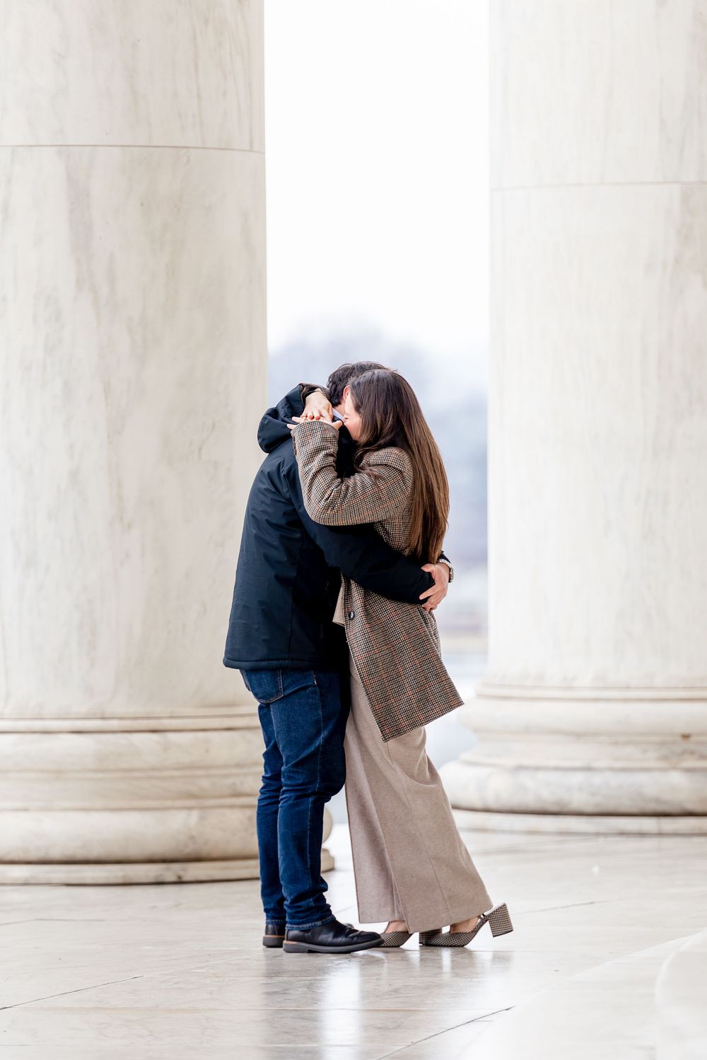 Couple sharing a romantic kiss between marble columns at the Jefferson Memorial in Washington DC.