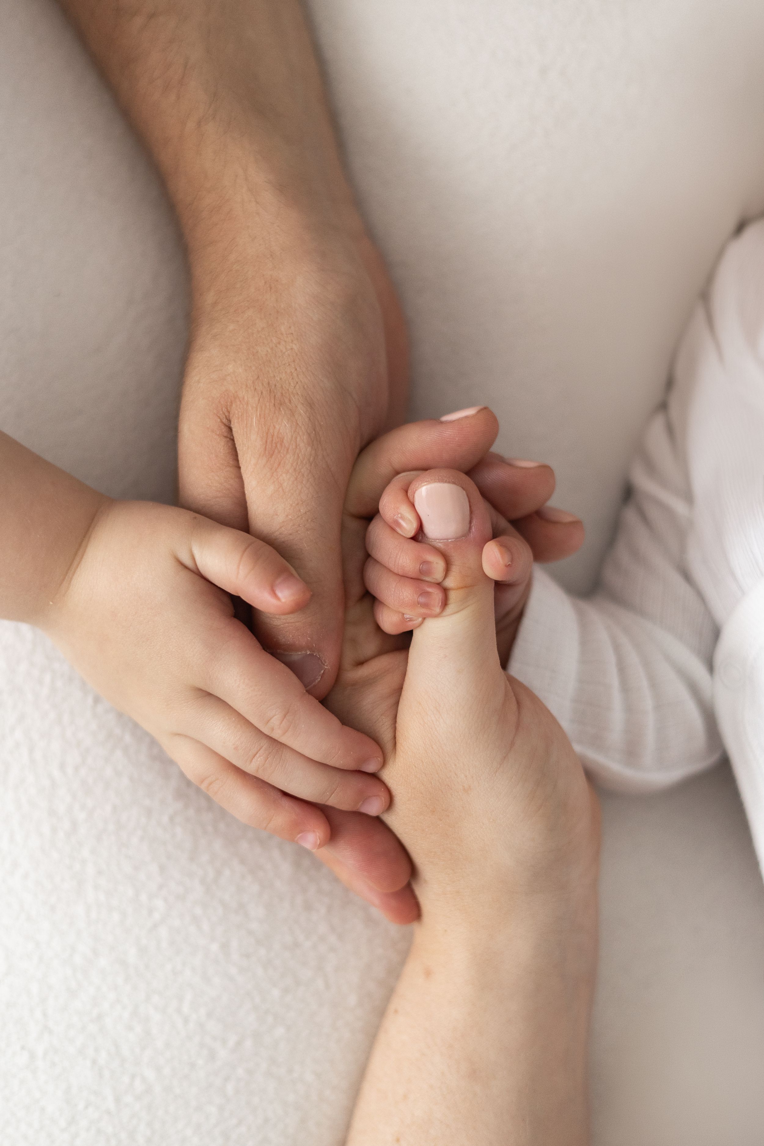 Family hands gently cradling a newborn baby's tiny hand, natural newborn photography Nottingham