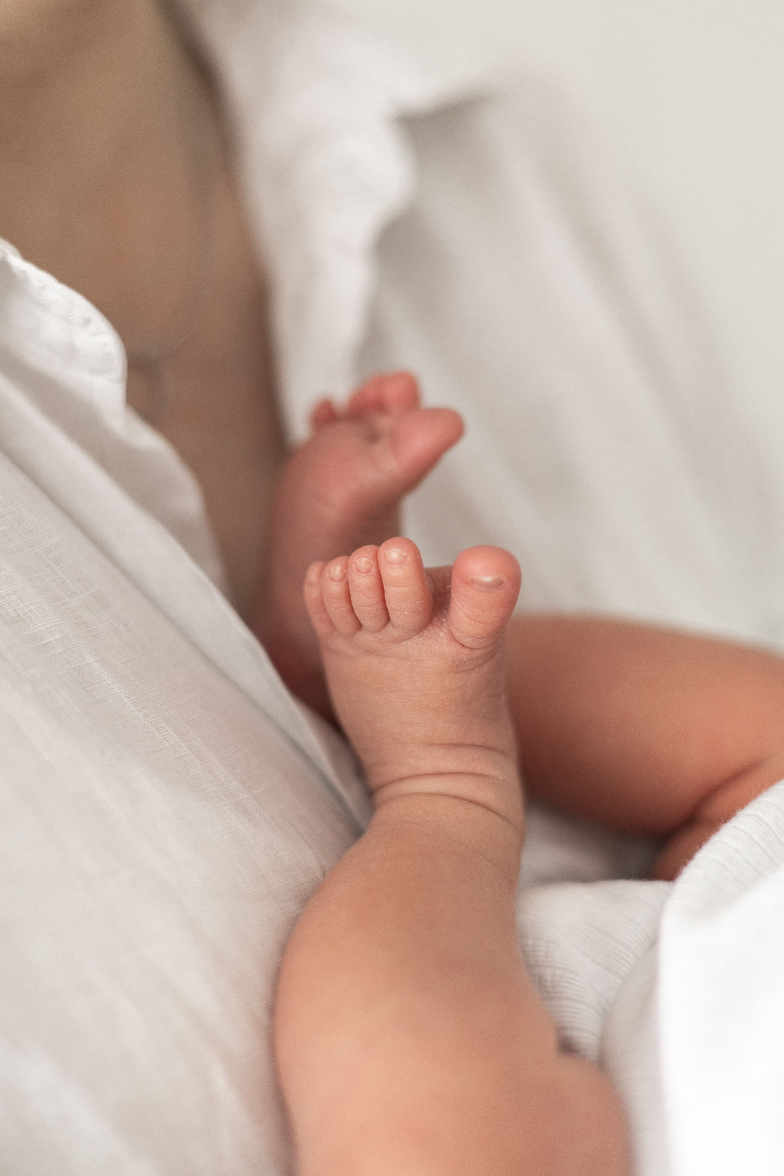 Close-up of tiny newborn baby feet while being cradled by mum natural newborn photography Nottingham