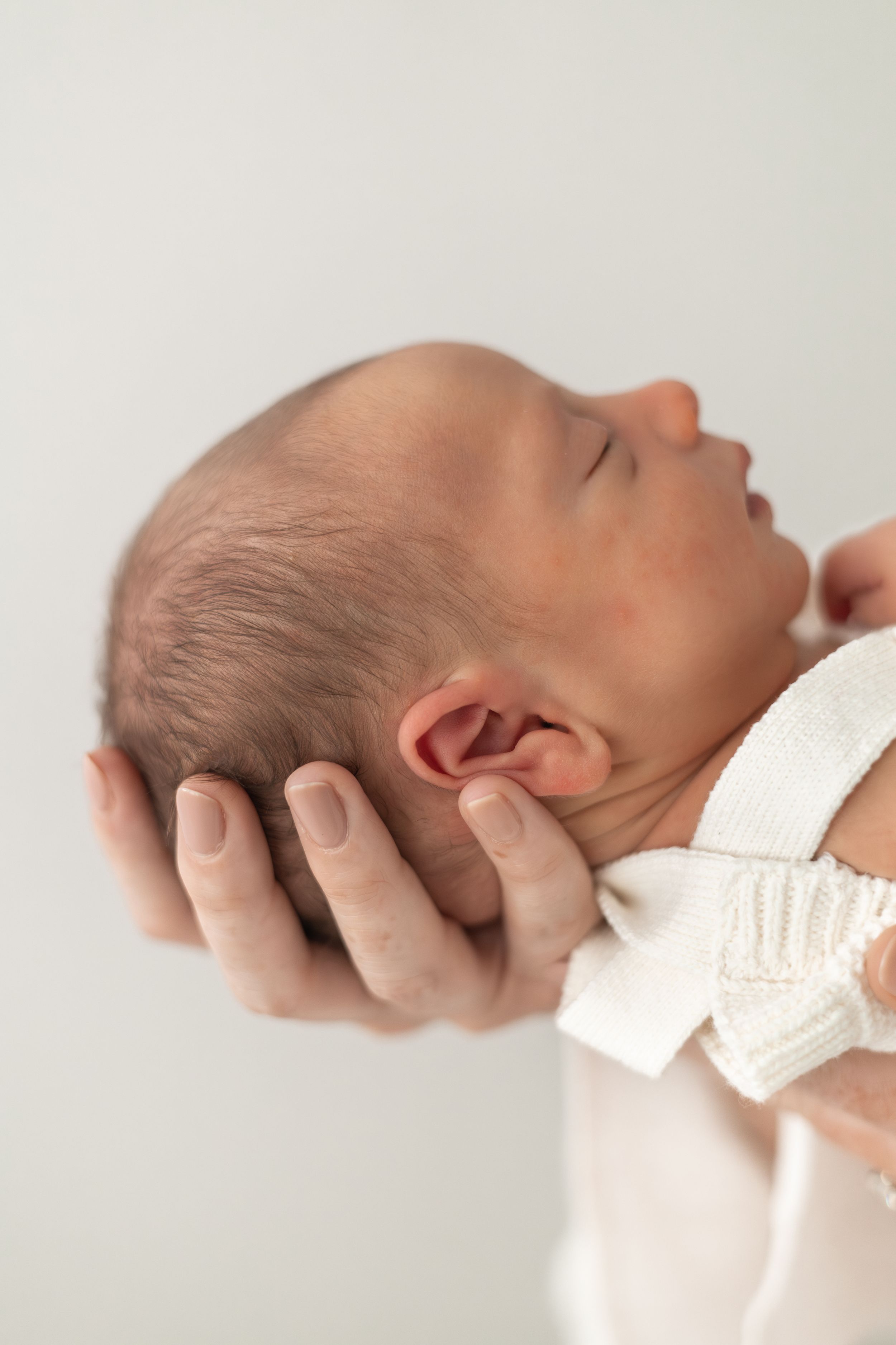 Close-up of a newborn baby sleeping peacefully while being gently cradled in a mothers hand natural newborn photography Nottingham