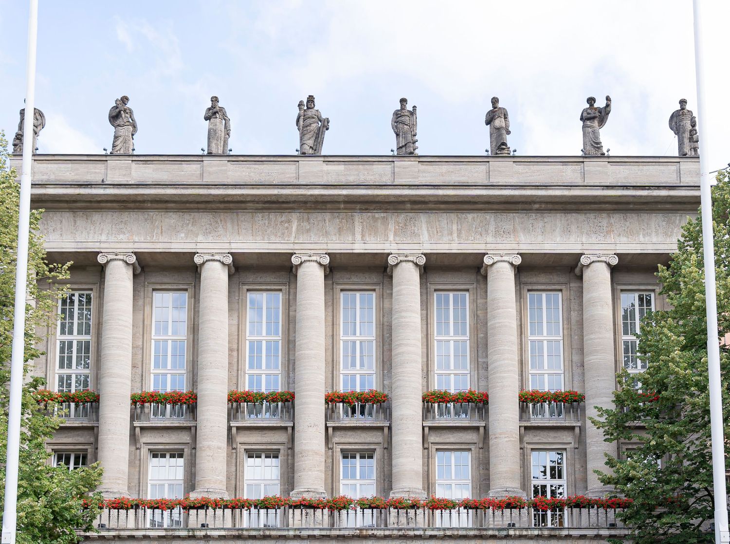 Neoclassical building facade with tall columns and statues along the roofline.