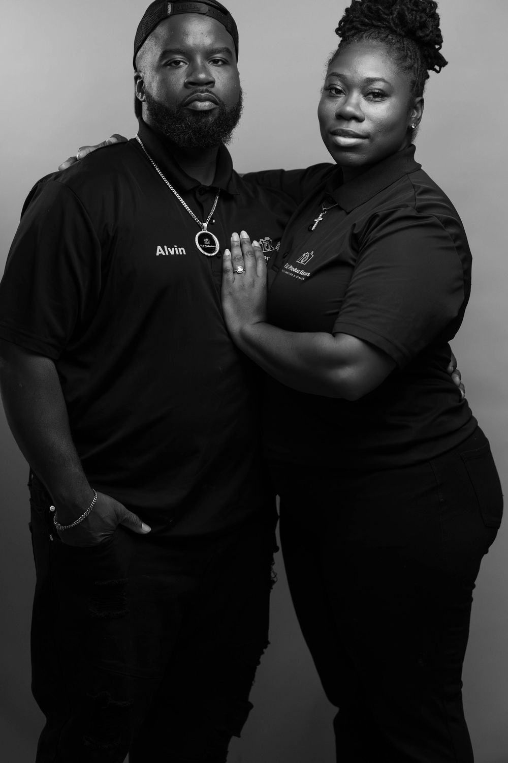 Black and white portrait of two people in matching black uniforms, man named Alvin and woman posing together.