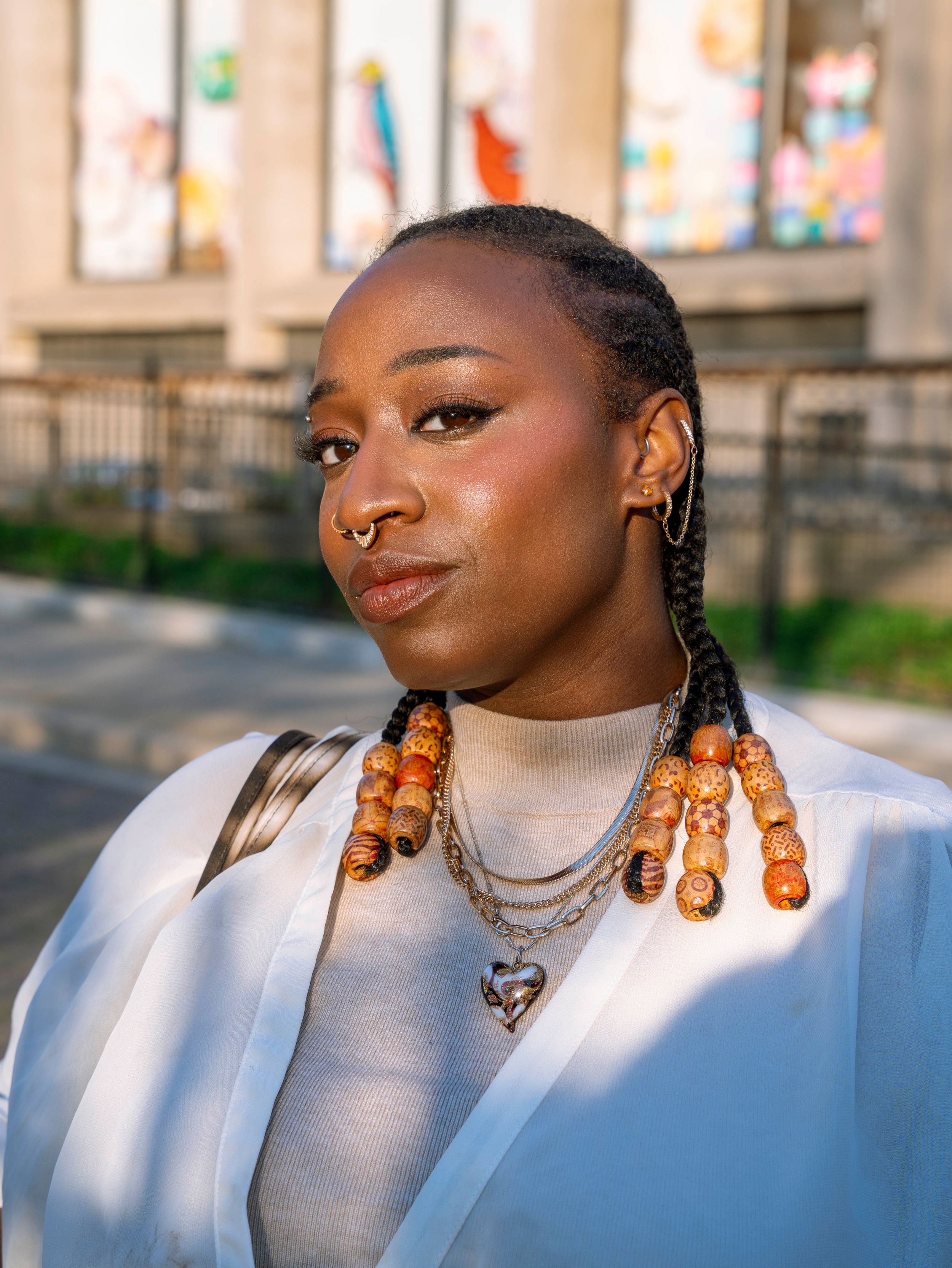 Close-up portrait of woman with braids and amber beaded necklaces layered with gold chains.