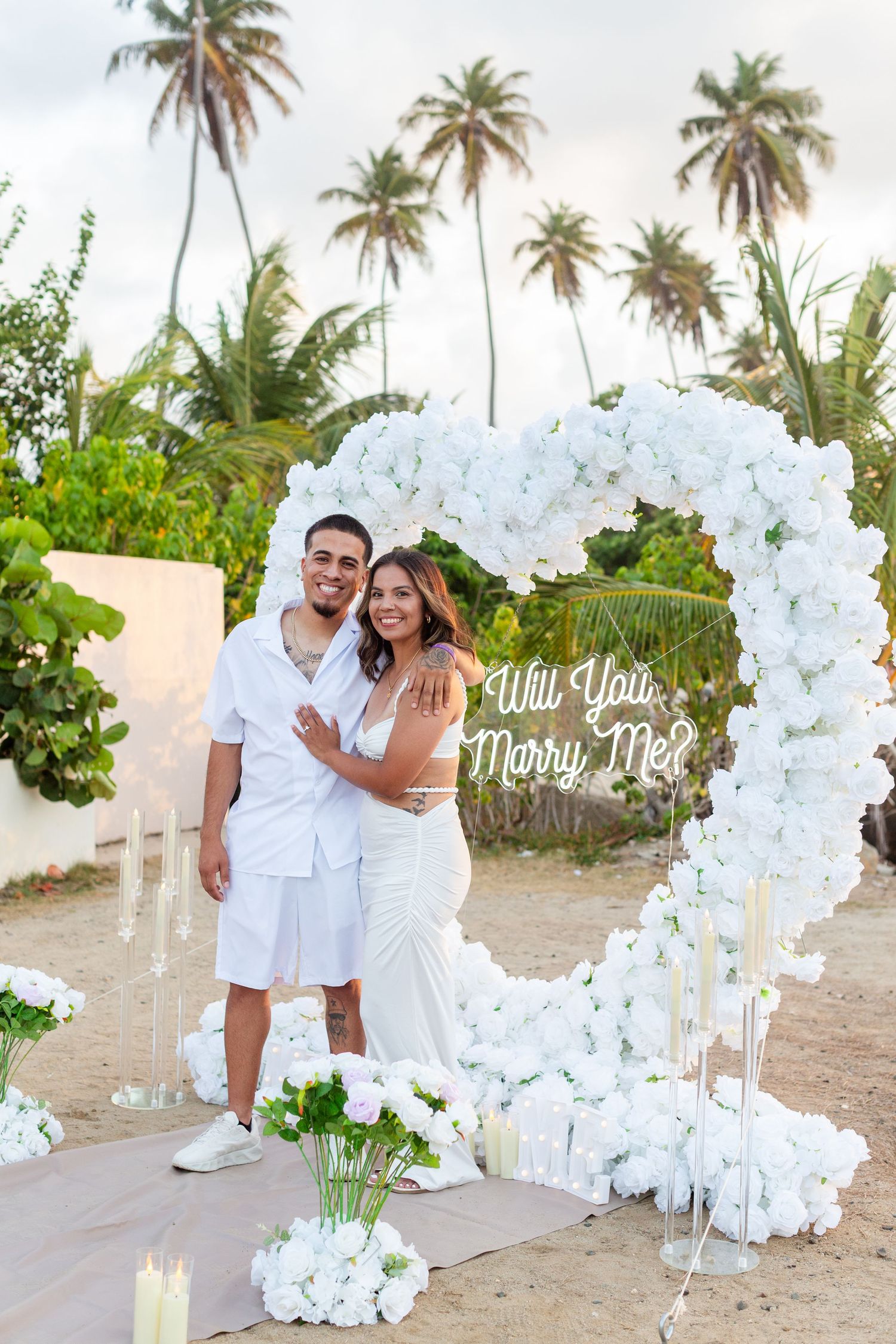 Marriage proposal. Man, woman, and decorative setup with white flower heart overlooking the ocean in Río Grande, Puerto Rico.