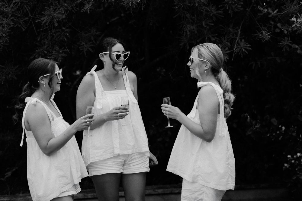Black and white photo series showing a couple in white outfits sharing intimate moments during an outdoor photoshoot.