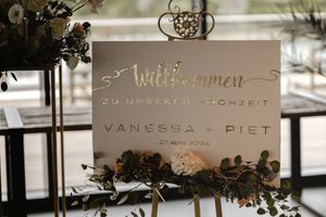 Wedding welcome sign for Vanessa and Piet on a gold easel decorated with greenery and flowers.