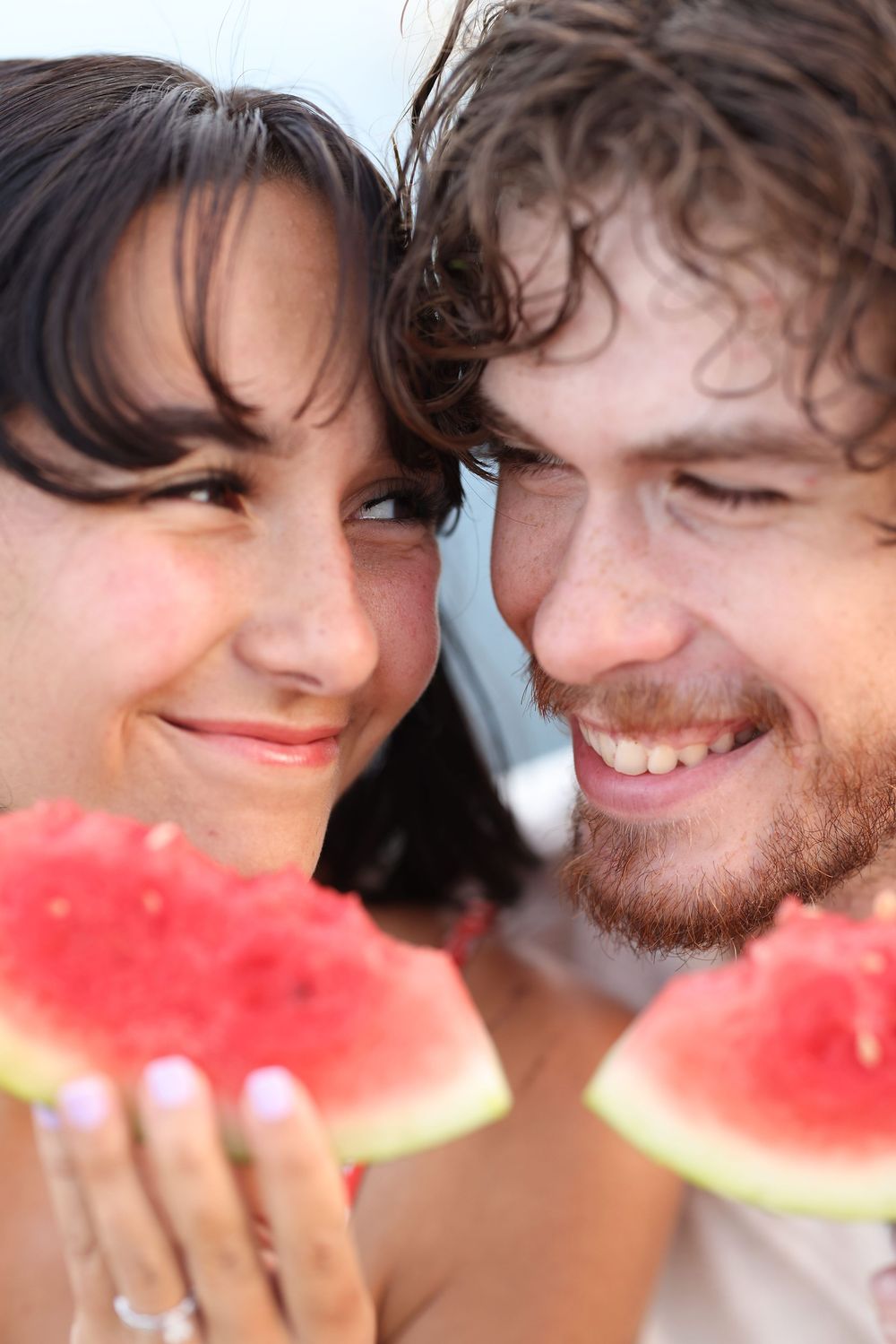Happy smiling couple holding watermelon slices close together enjoying a fun summer moment.