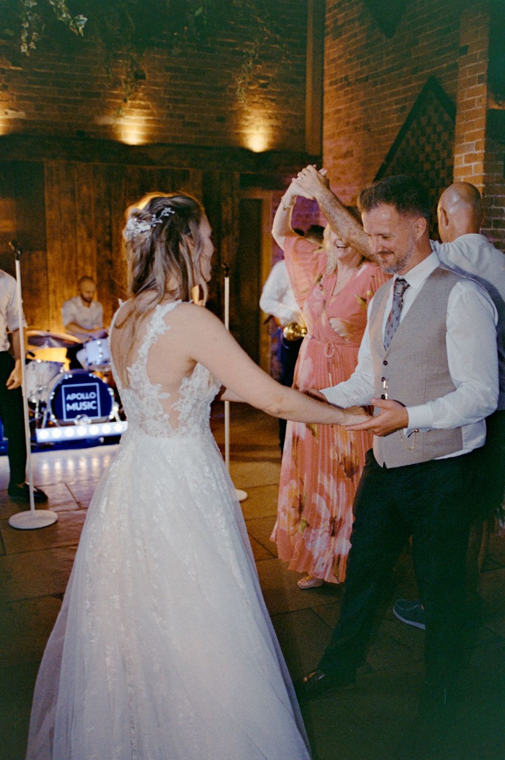 Bride and groom share first dance at wedding reception with live band performing in rustic brick venue.
