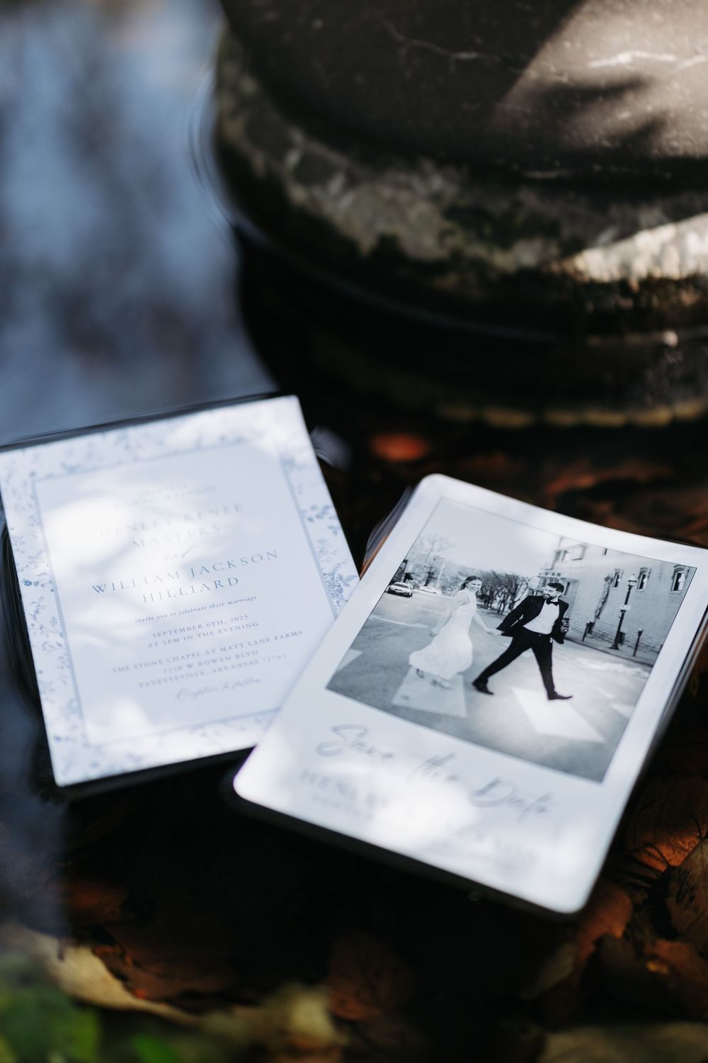 Wedding invitation and save-the-date card with black-and-white couple photo displayed on a rustic stone surface.