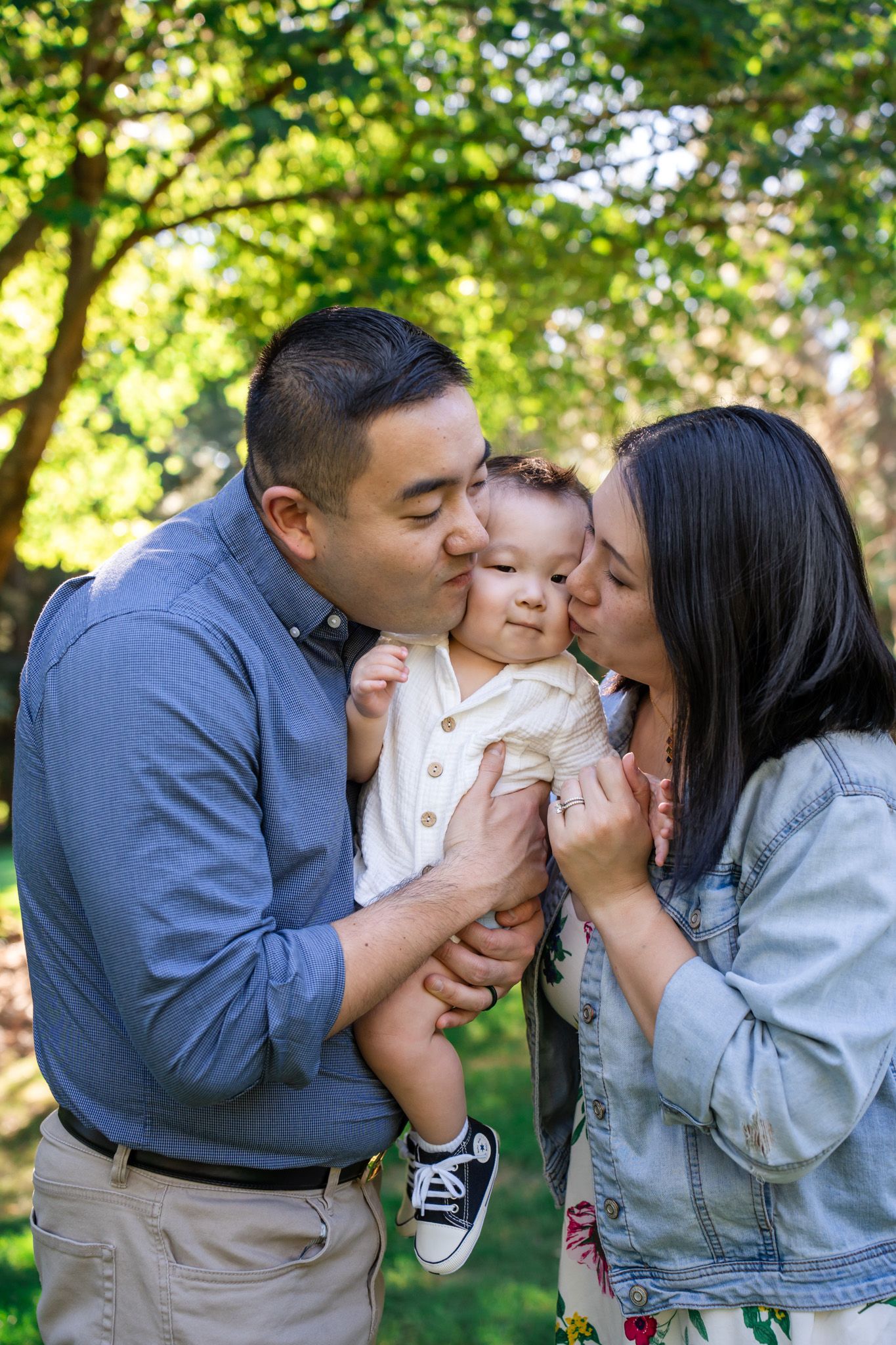 Mom and dad kiss baby boy family portrait