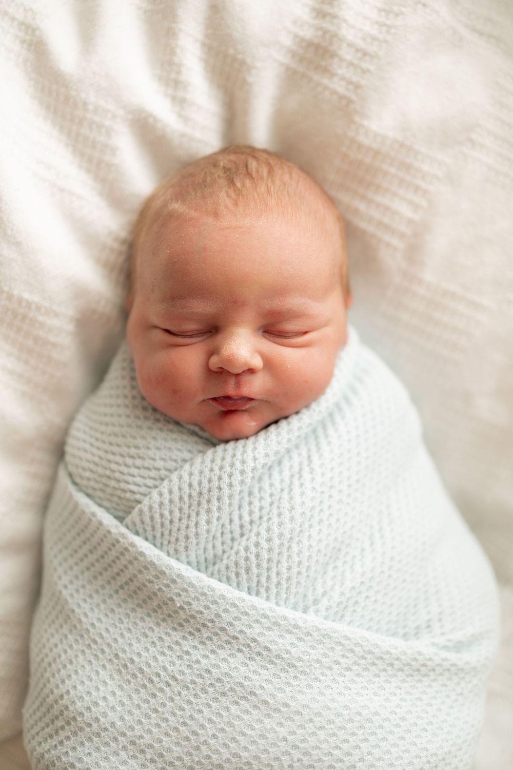 Peaceful newborn baby swaddled in a soft light blue knit blanket at Parkwest Medical Center in Knoxville, TN.