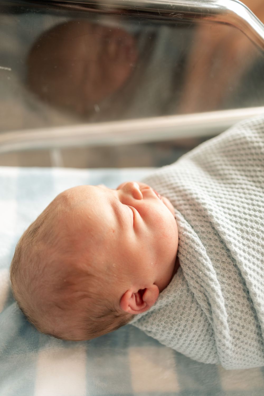 Newborn baby swaddled in a white knit blanket lying in a hospital bassinet for a newborn photo at Parkwest Medical Center in Knoxville, TN.