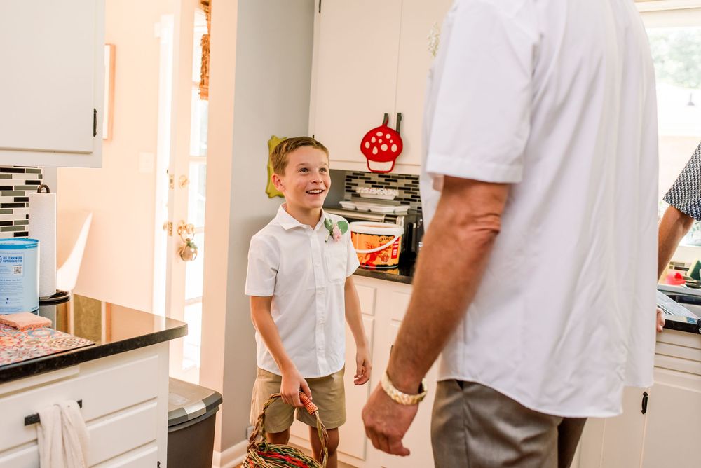 Young smiling boy in white shirt interacting with adult man in bright kitchen interior.
