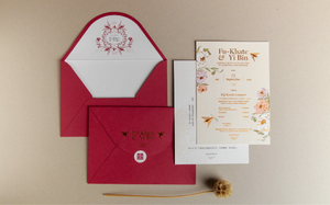Romantic red envelope and floral wedding invitation suite with watercolor botanical design on neutral background.