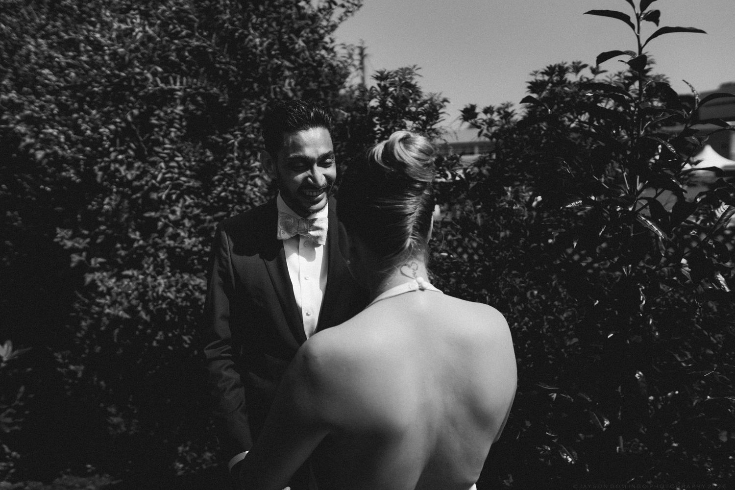 Black and white photo of smiling groom seeing bride for first time at outdoor first look.