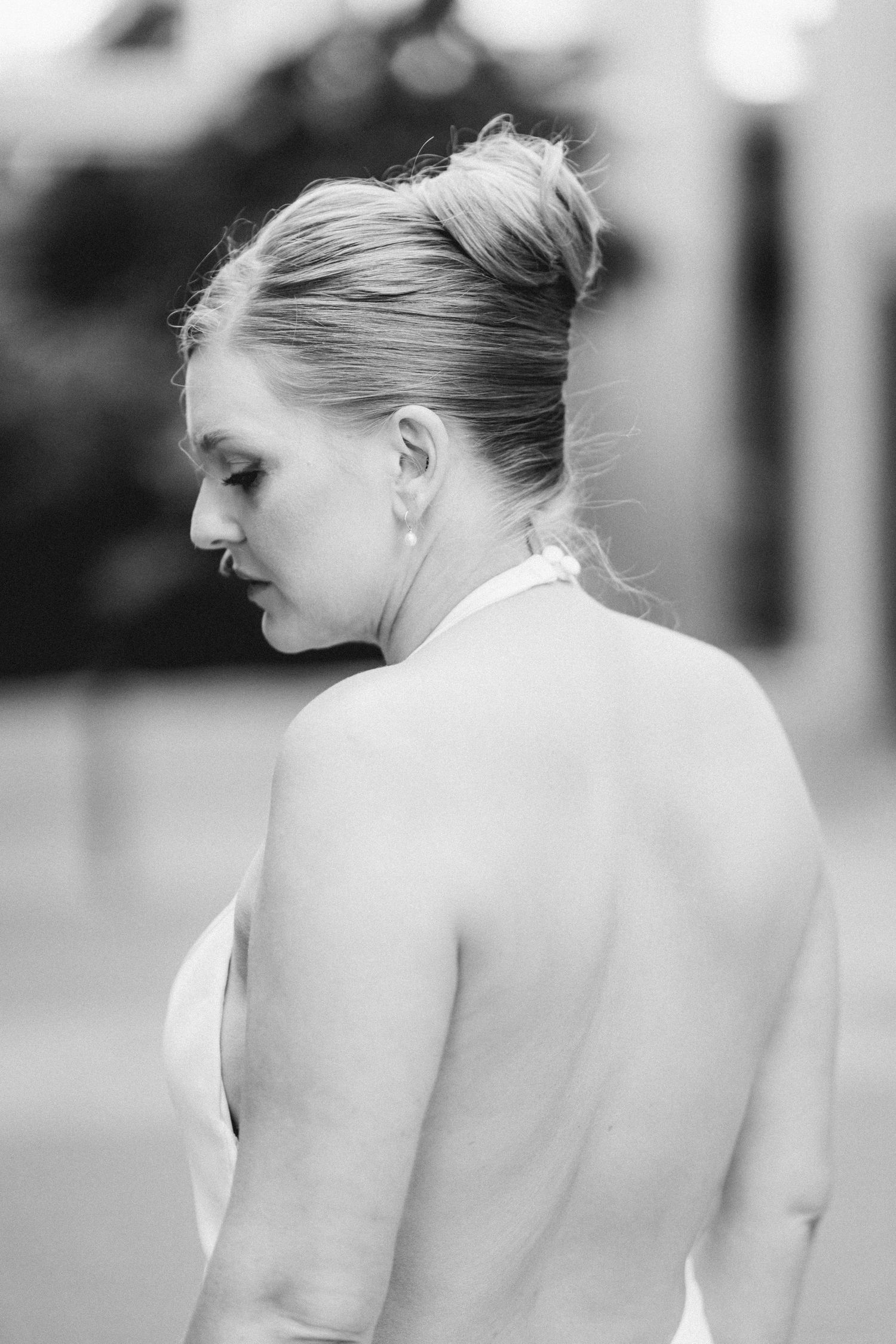 Black and white portrait of a bride with updo hairstyle showing elegant bare back in wedding dress.