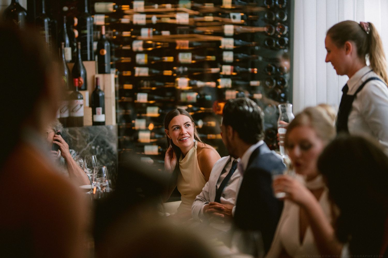 Guests enjoying conversation and wine at an intimate restaurant wedding reception.