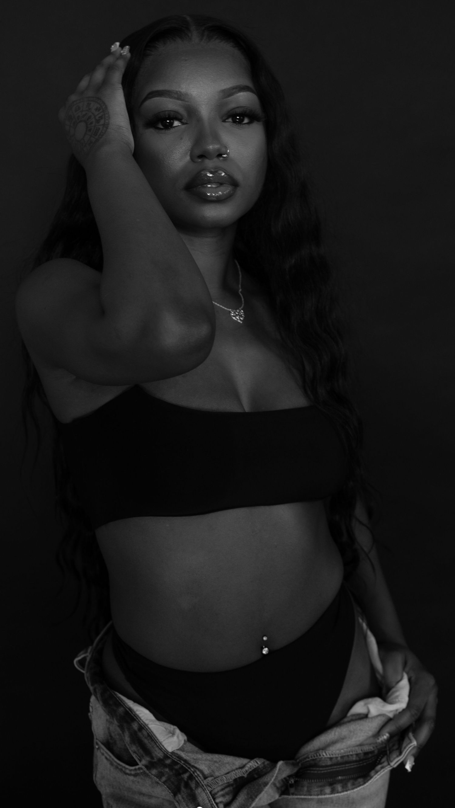 Black and white portrait of woman in crop top and jeans in studio.