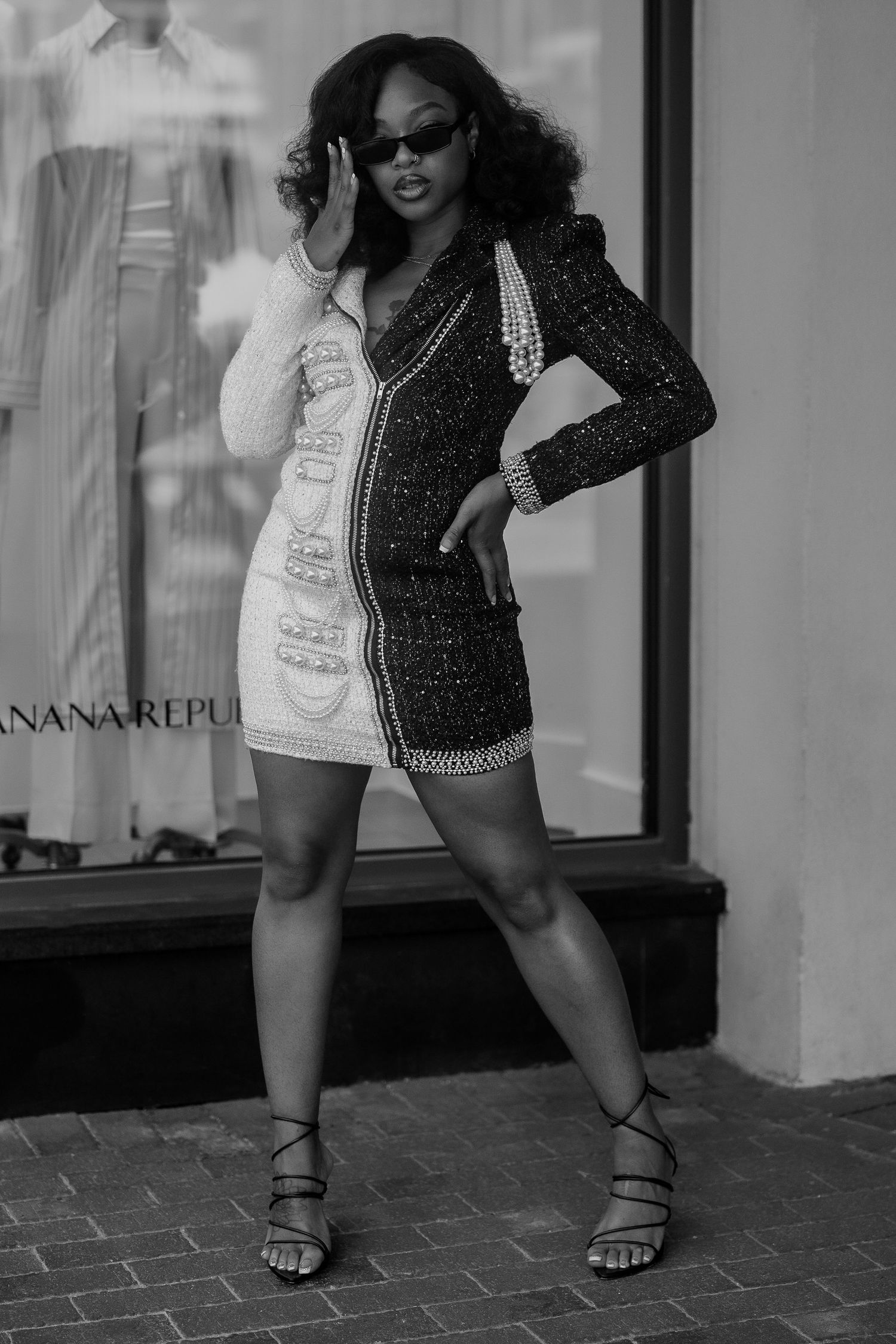 Black and white photo of a woman in a sequined mini dress and heels posing outside Banana Republic.