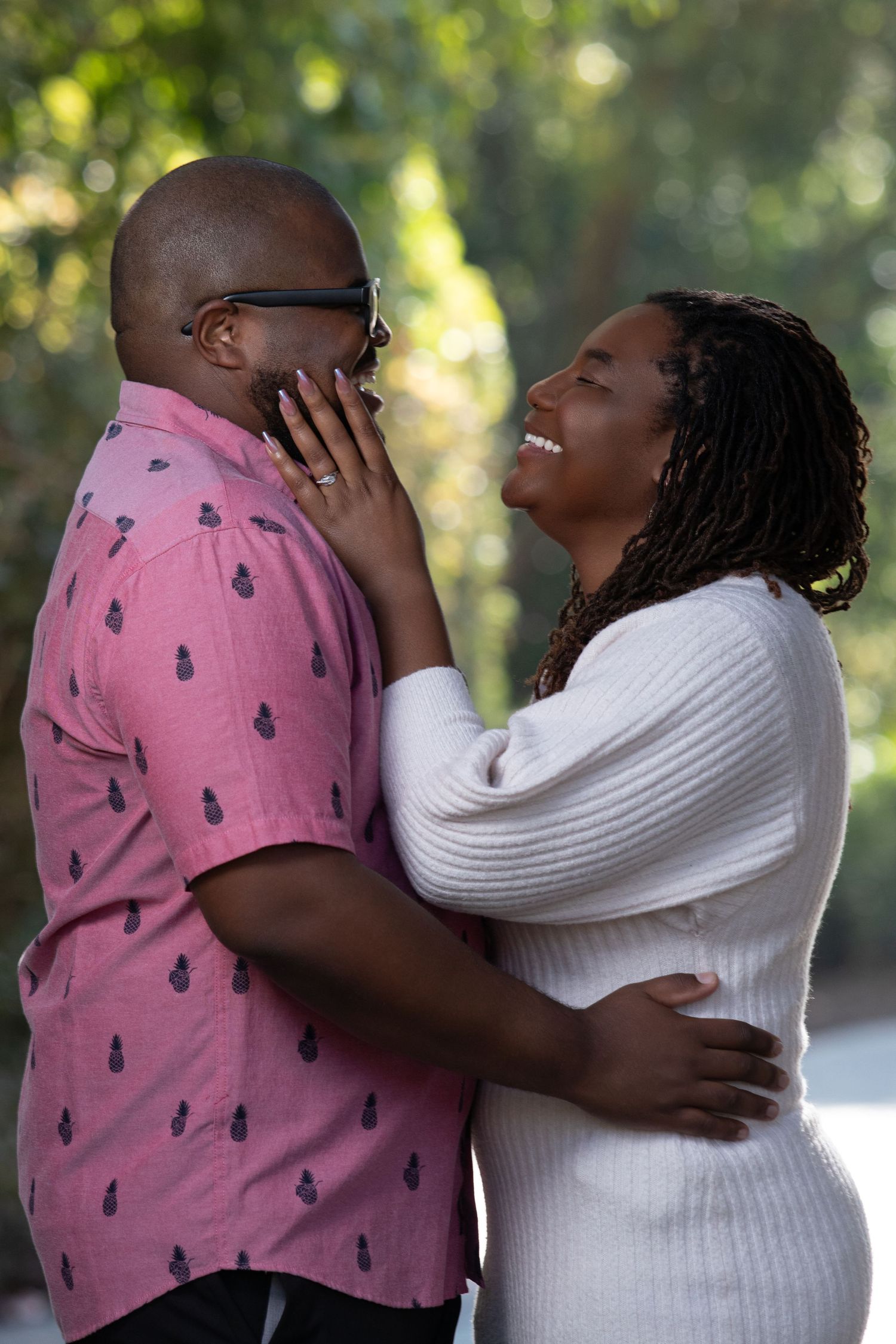 Black and white photo of a loving couple embracing outdoors, woman tenderly touching mans face.
