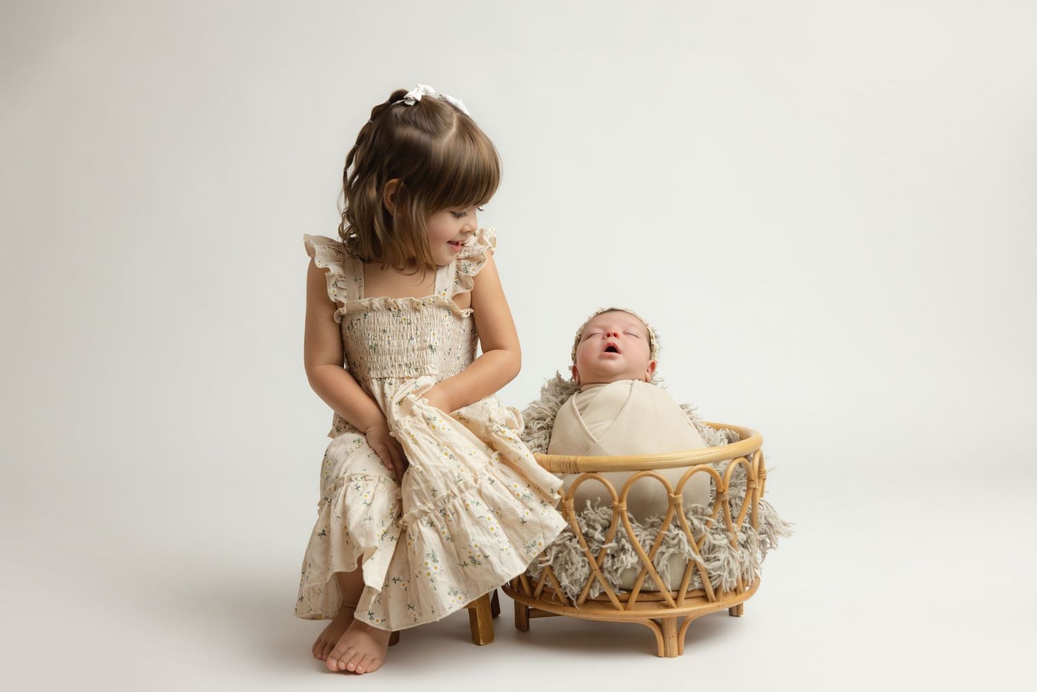 Newborn baby in teal hooded knit onesie with wooden buttons, sitting in a vintage metal bucket with soft teal blankets.