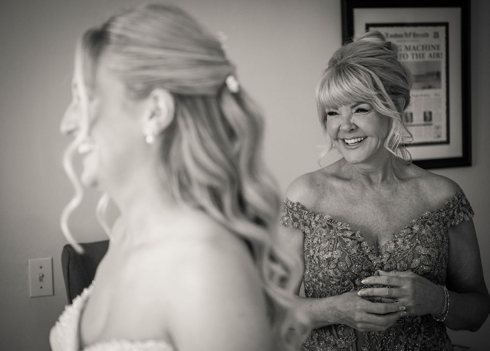 Black and white photo of bride and smiling mother in elegant beaded gown before wedding.