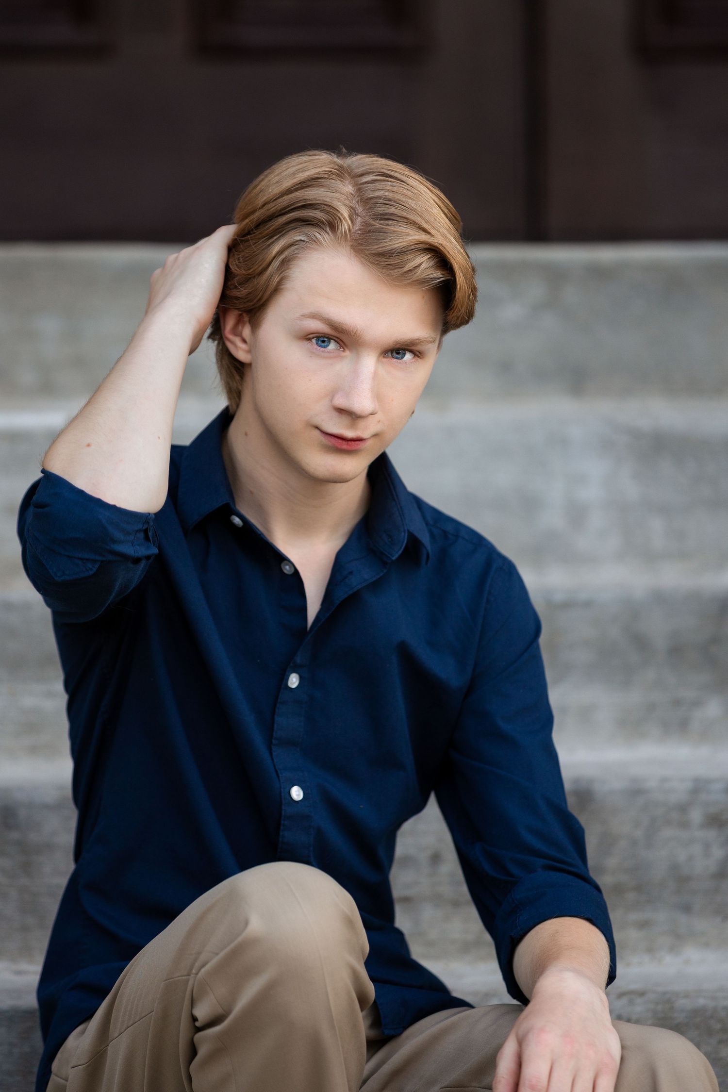 High school senior guy adjusting his hair at outdoor senior pictures in downtown Howell, Michigan by South Lyon, MI portrait photographer