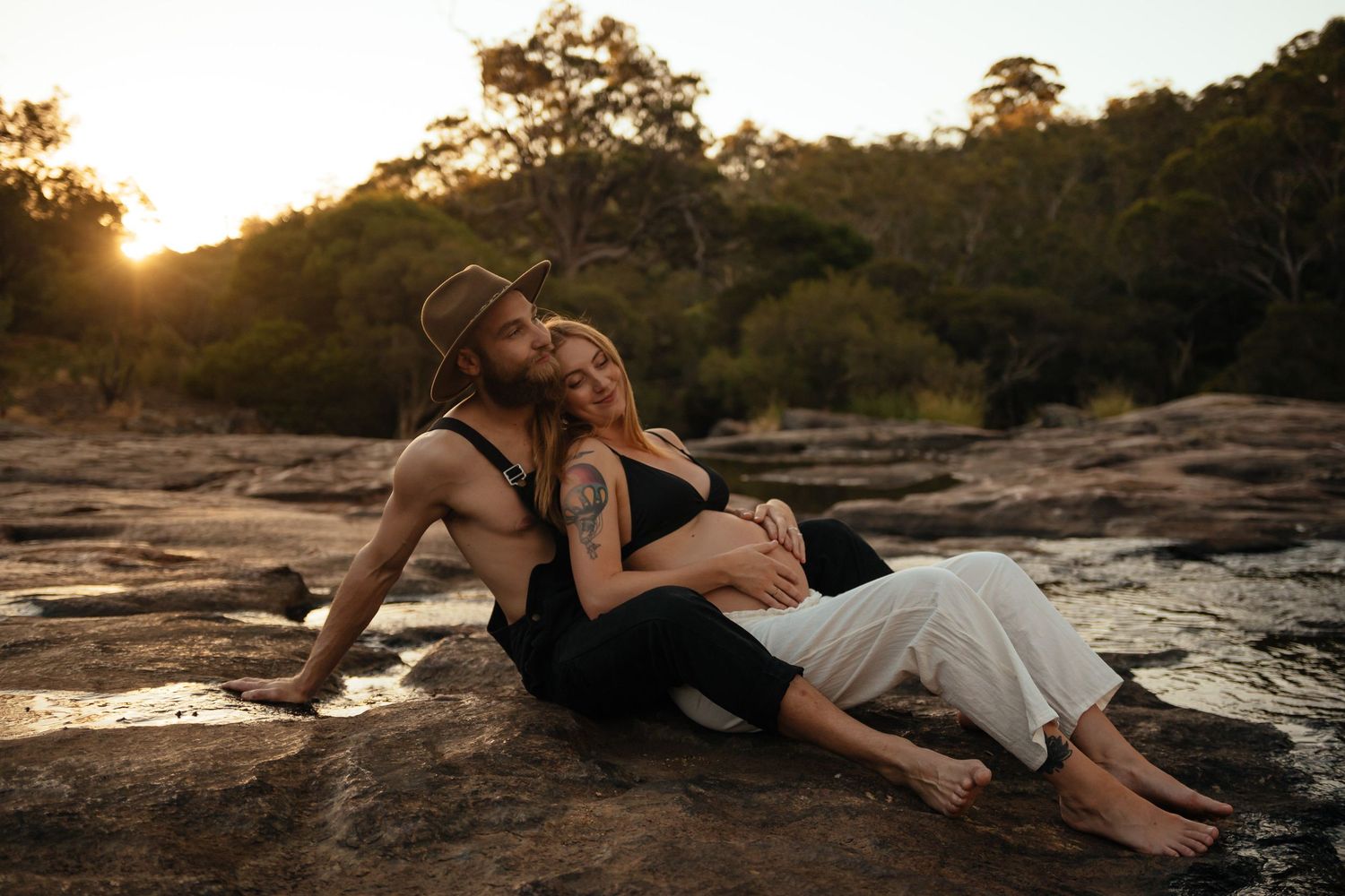 Roleystone maternity session with an expectant couple embracing beside the rock pools in a peaceful natural setting.