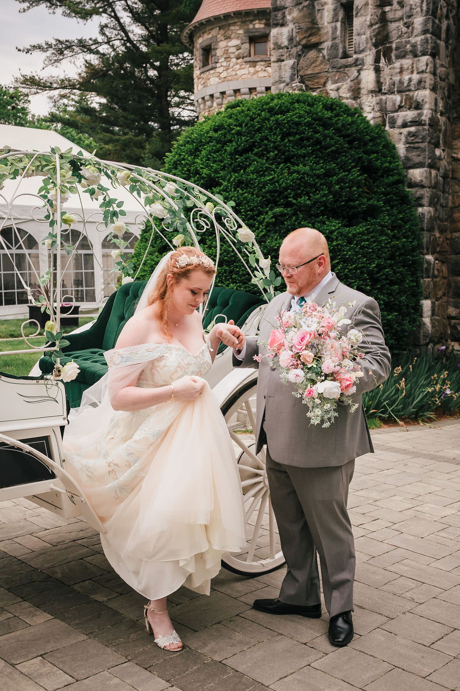Bride's father helping her step down from the carriage, holding her bouquet, at Searles Castle.